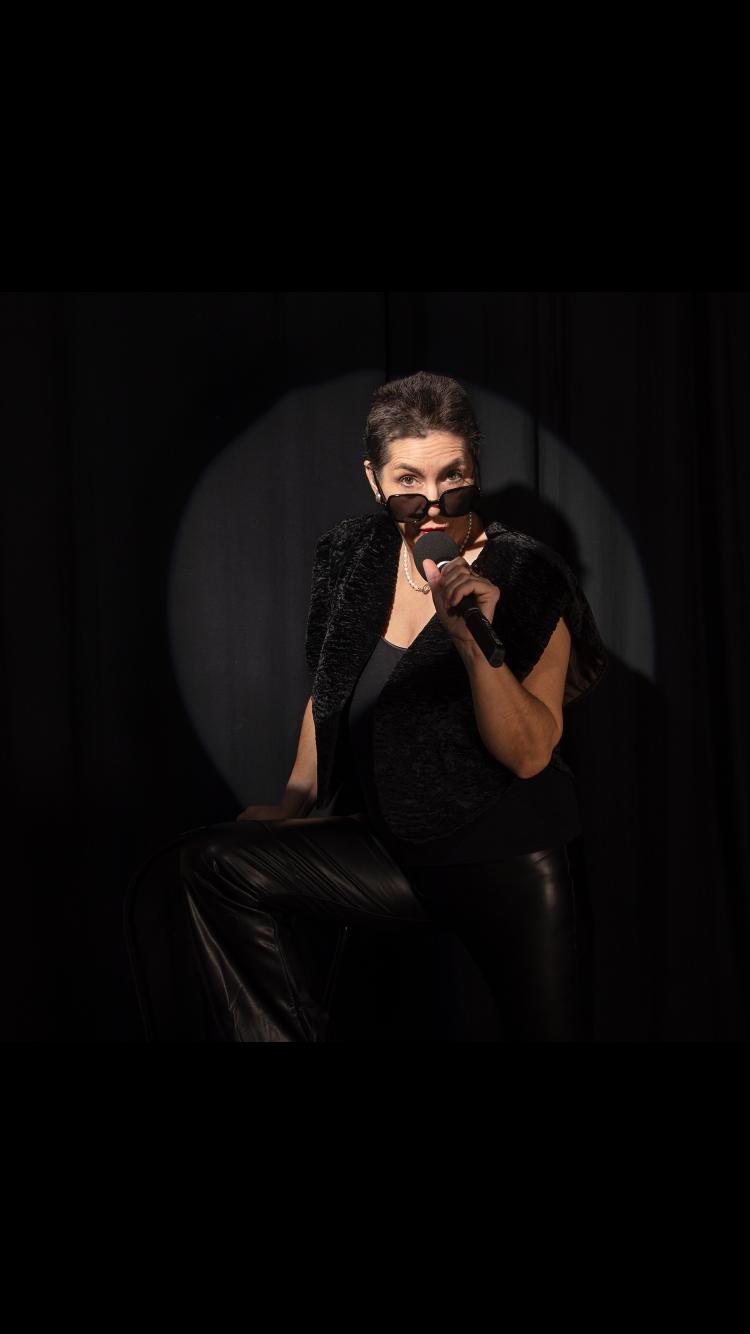 Marion Neuendorf auf der Bühne – dramatisches Spotlight, Mikrofon in der Hand